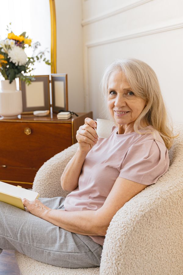 A senior client enjoying tea and a book at home